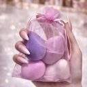 Hand holding the organza pouch containing four makeup blender sponges