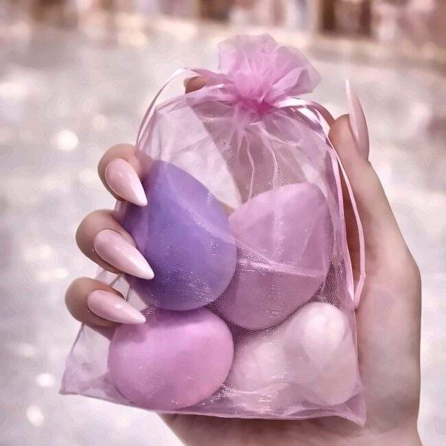 Hand holding the organza pouch containing four makeup blender sponges